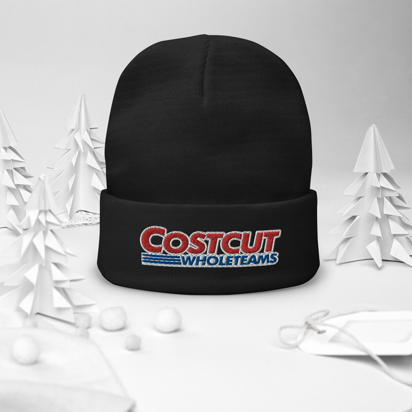 A black beanie with red and blue text "Cost cut whole teams" embroidered in the style of the "Costco Wholesale" logo, on a festive winter background surrounded by pine trees